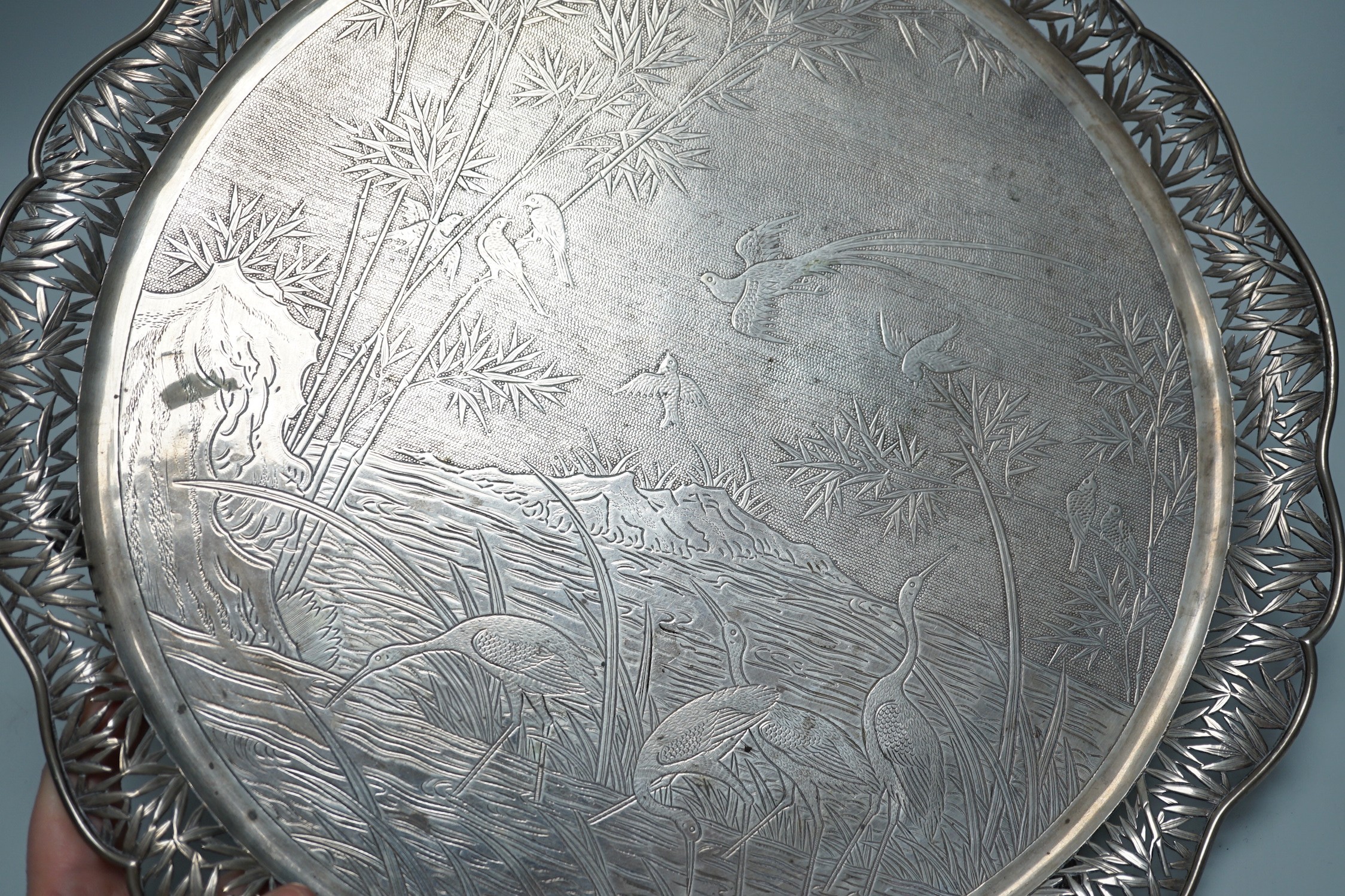 A Chinese Export white metal circular salver with pierced foliate wavy border and engraved with birds amongst reeds and bamboo, maker's mark, WHL, 33.7cm, 36oz.